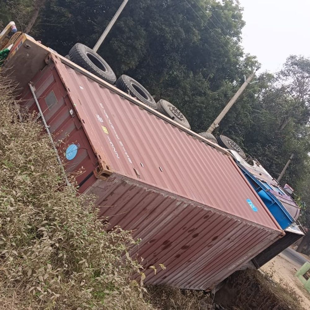 रजौन में अजीत नगर पुल के पास कंटेनर पलटा:घने कोहरे के कारण खाई में गिरा, चालक-खलासी घायल